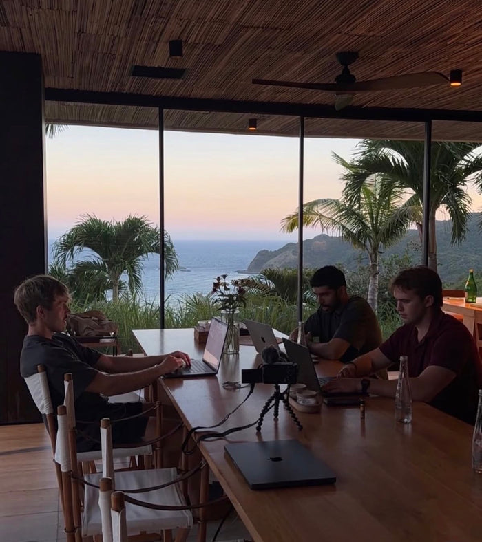 The Audens team working at a long table overlooking the ocean at sunset