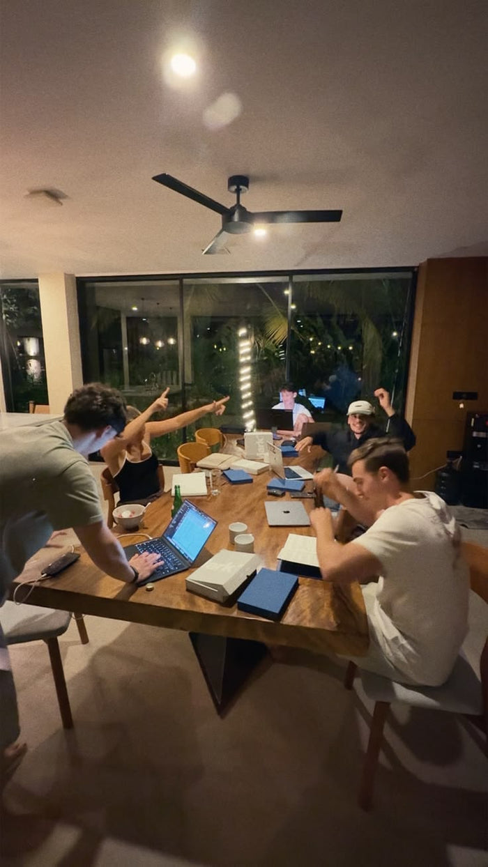 The Audens team celebrating around a work table late at night
